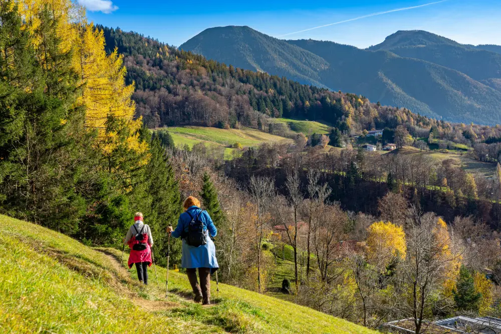 wei Seniorinnen wandern auf dem Tegernseer Höhenweg mit Blick auf den Wallberg.